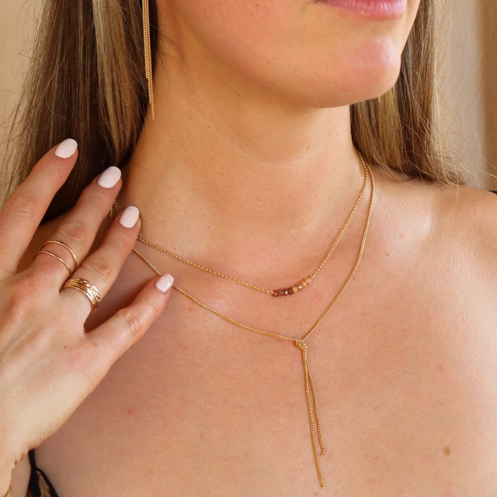 model wearing 14k gold fill chain necklace with topaz stones wrapped to it paired with a 14k gold fill chain lariat necklace