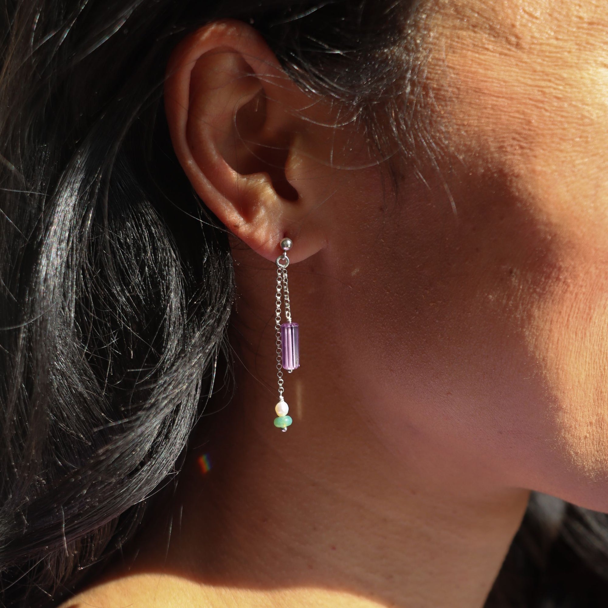 sterling silver stud earrings with chain, purple zircon tubes, pearls, and moss agate on a light background