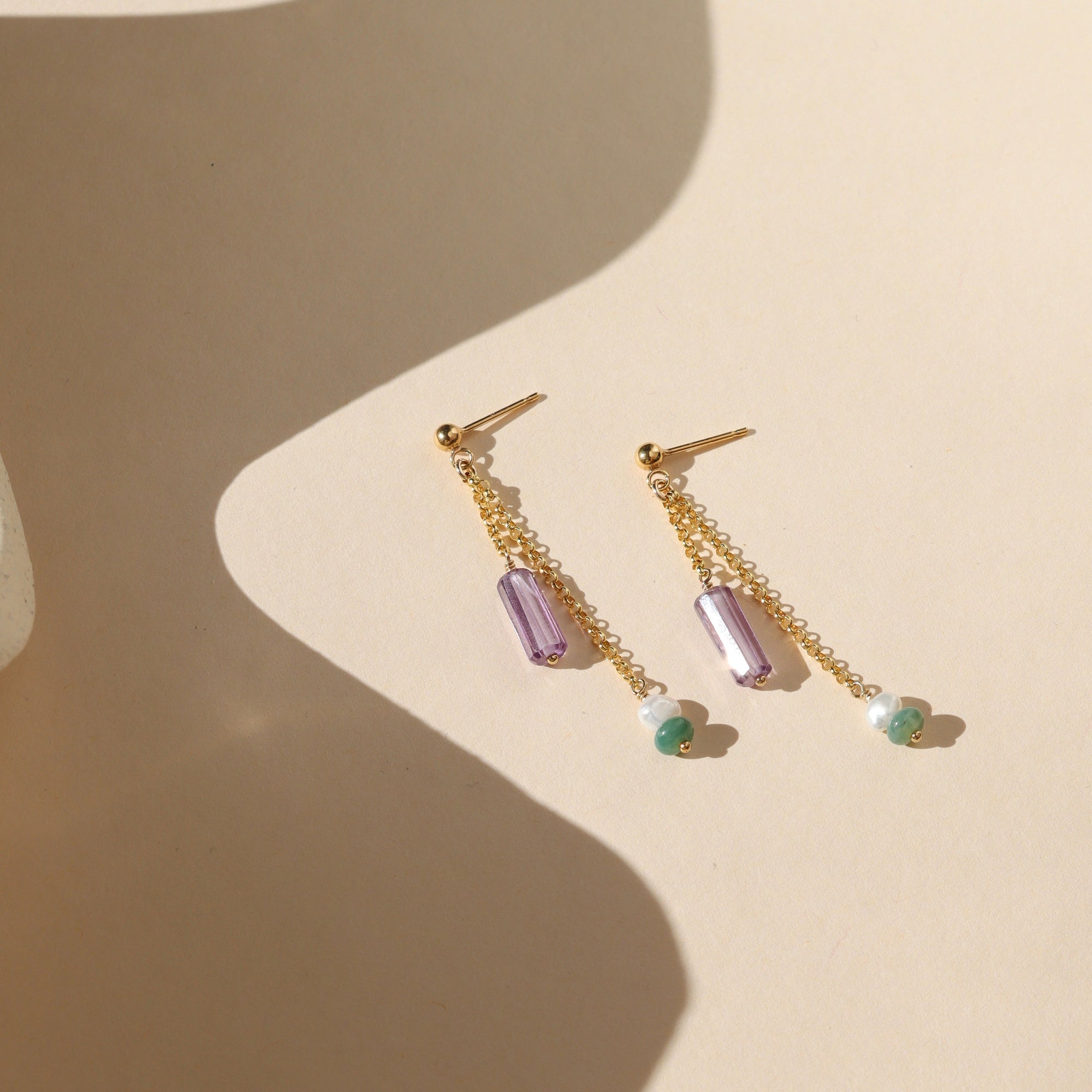 14k gold fill stud earrings with chain, purple zircon tubes, pearls, and moss agate on a light background