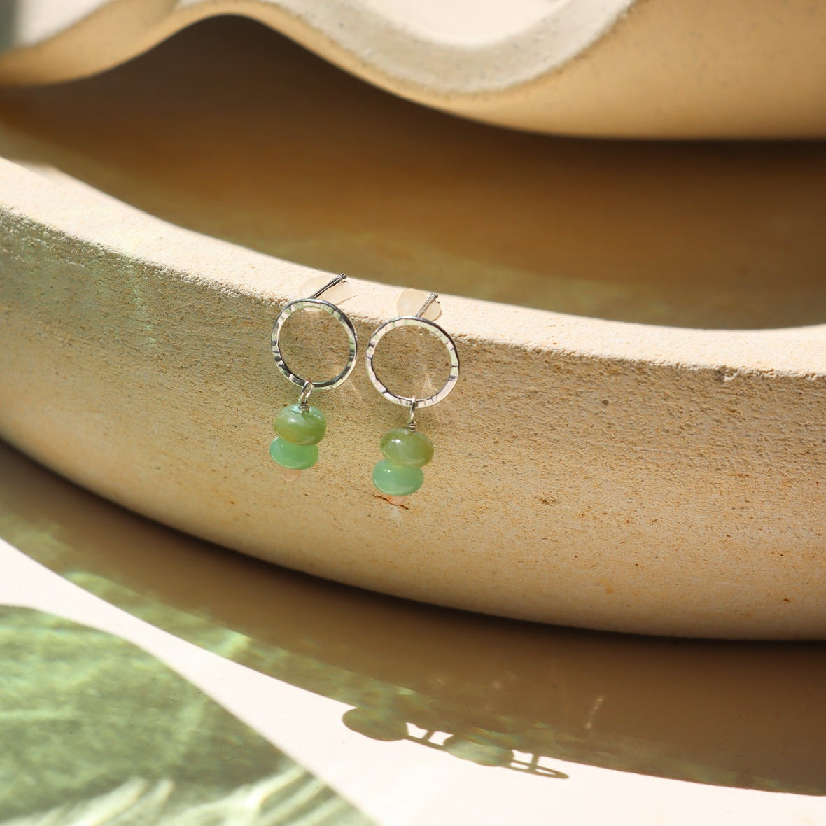sterling silver circle studs with opals and coral beads on a light dish