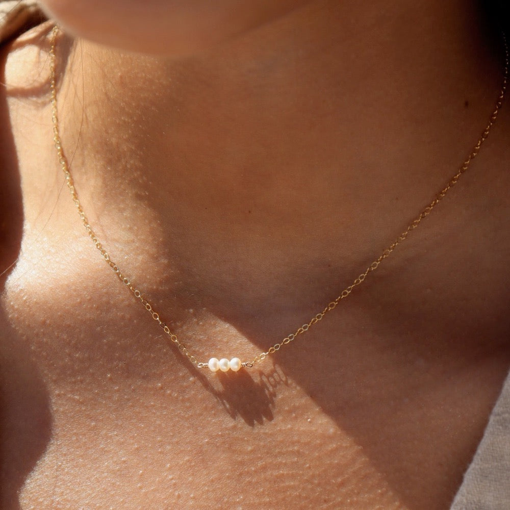 model wearing three freshwater pearls lined up on a 14k gold fill simple chain