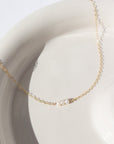 three freshwater pearls lined up on a 14k gold fill simple chain, made by Token Jewelry , photographed on a white ceramic dish