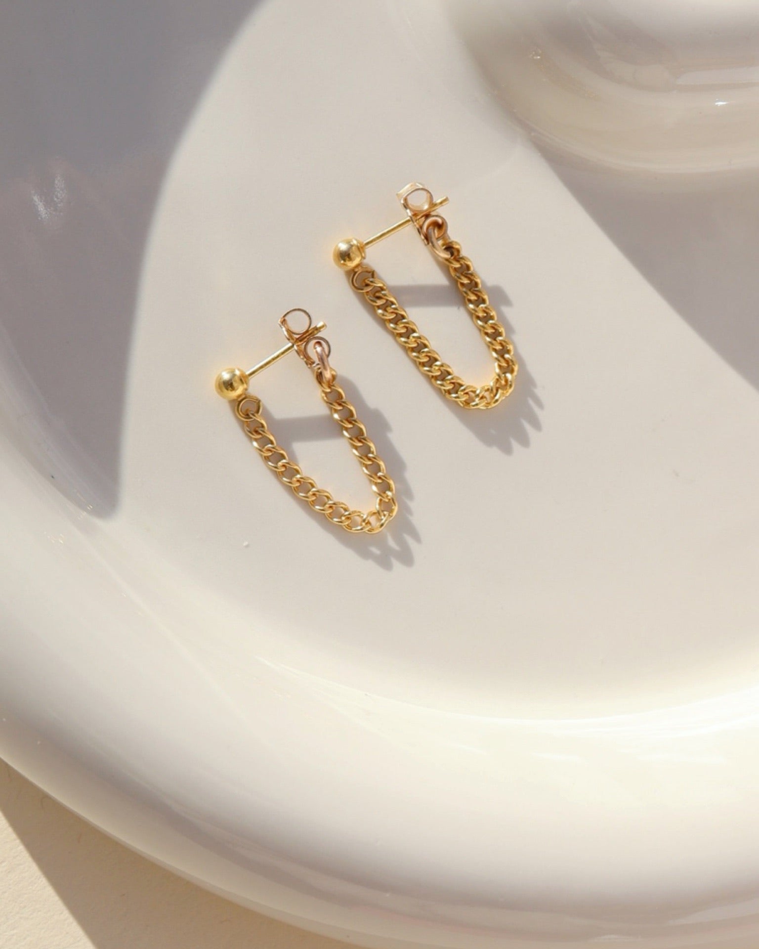 14k gold fill small curb chain stud earrings on a light dish