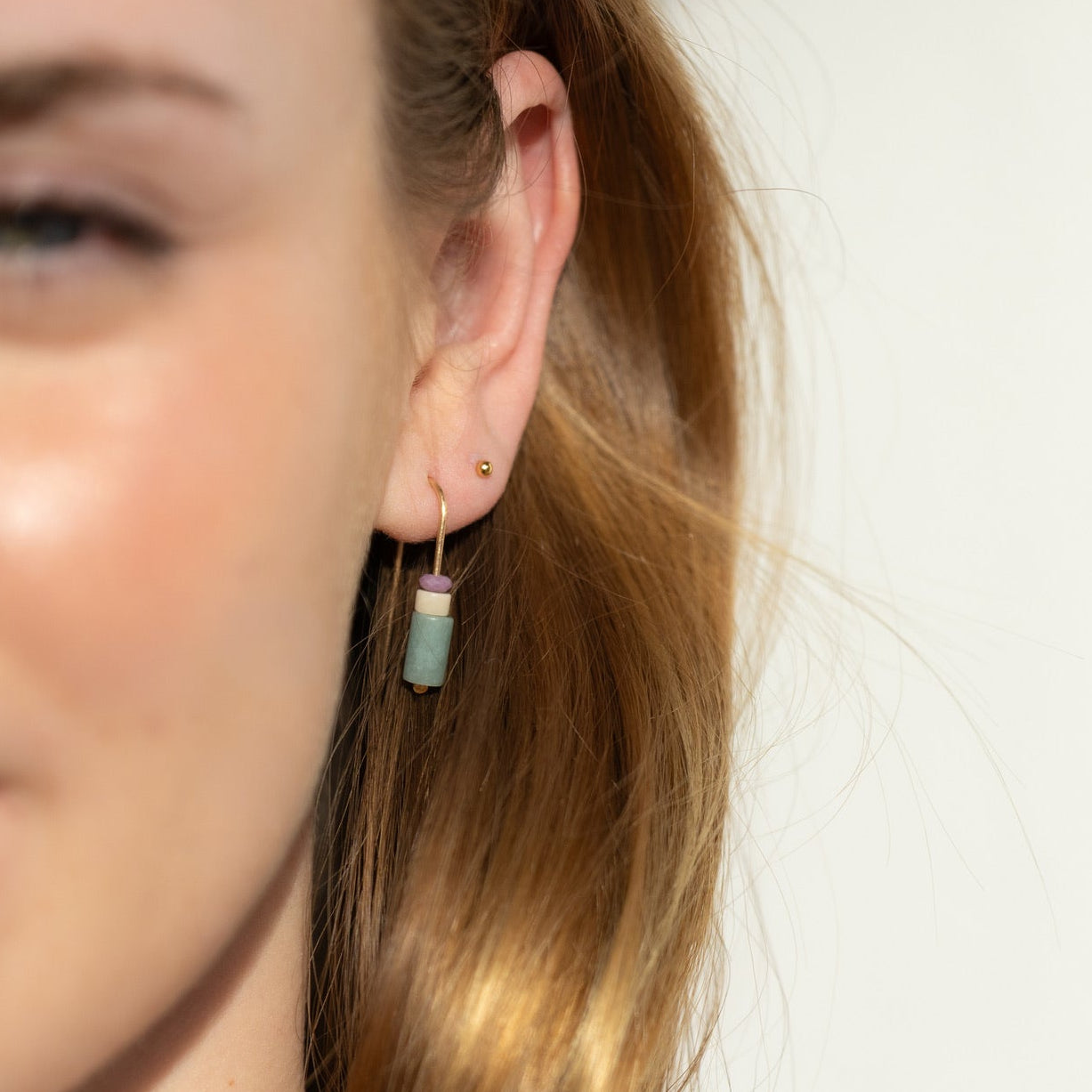 Model wearing 14k gold fill arch earrings with gemstone beads