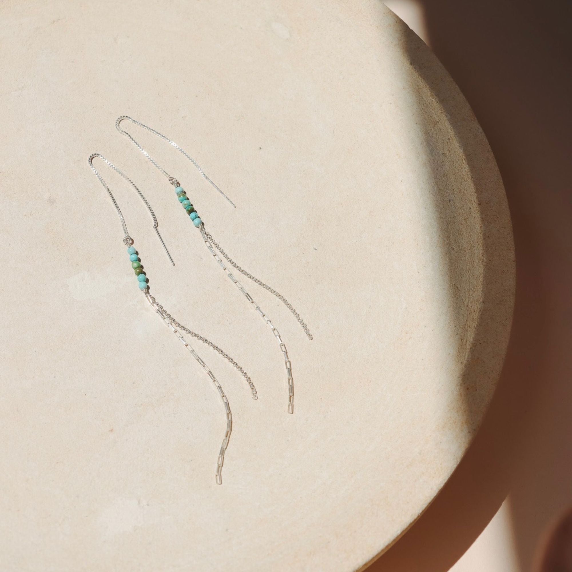 sterling silver threader style earrings with turquoise beads in the sunlight
