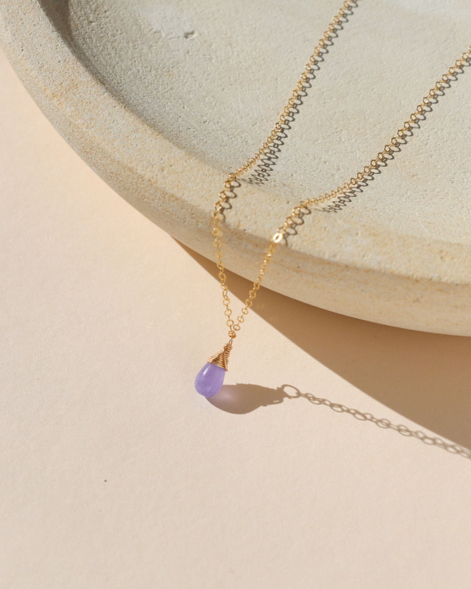 delicate 14k gold fill chain necklace with teardrop hackmanite pendant on a light dish
