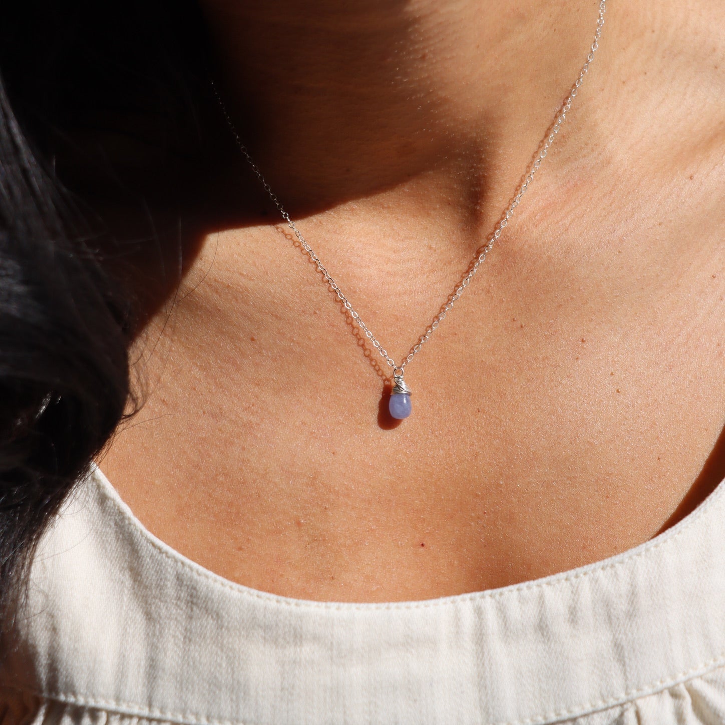 model wearing sterling silver dainty chain necklace with Heckmanite stone