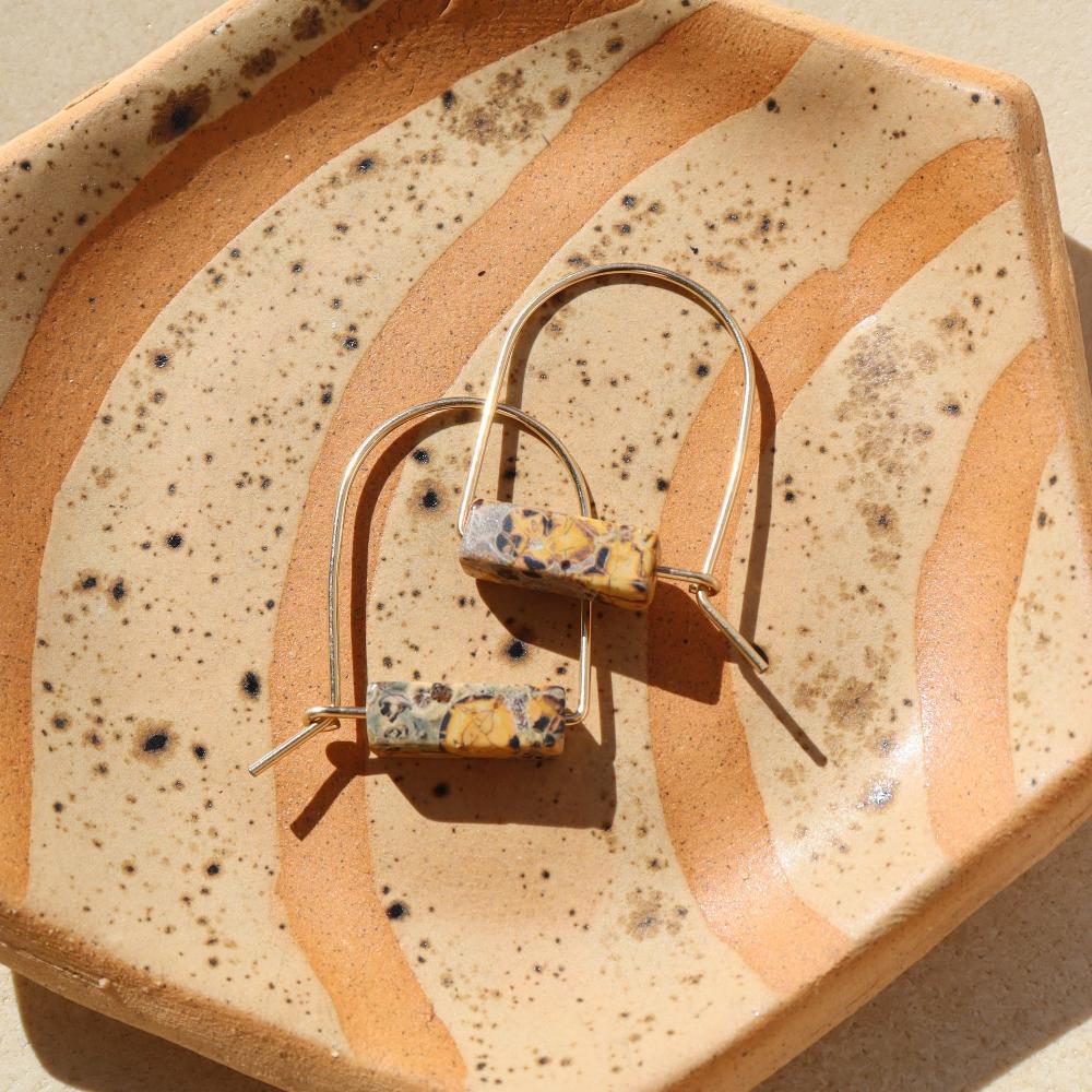 14k gold fill hand shaped arch earrings with leopard jasper stones on a light background