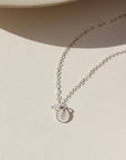 A sterling silver simple chain with a stamped disc with a small bunny, paired with a small opal wire wrapped gemstone. 