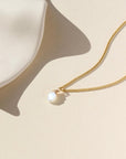 Delicate gold curb chain, with moonstone slice gemstone. Displayed on a cream backdrop. 