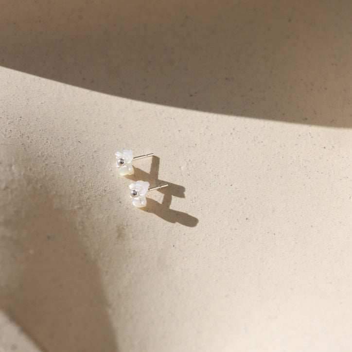 sterling silver stud earrings with mother of pearl flower beads on a light dish
