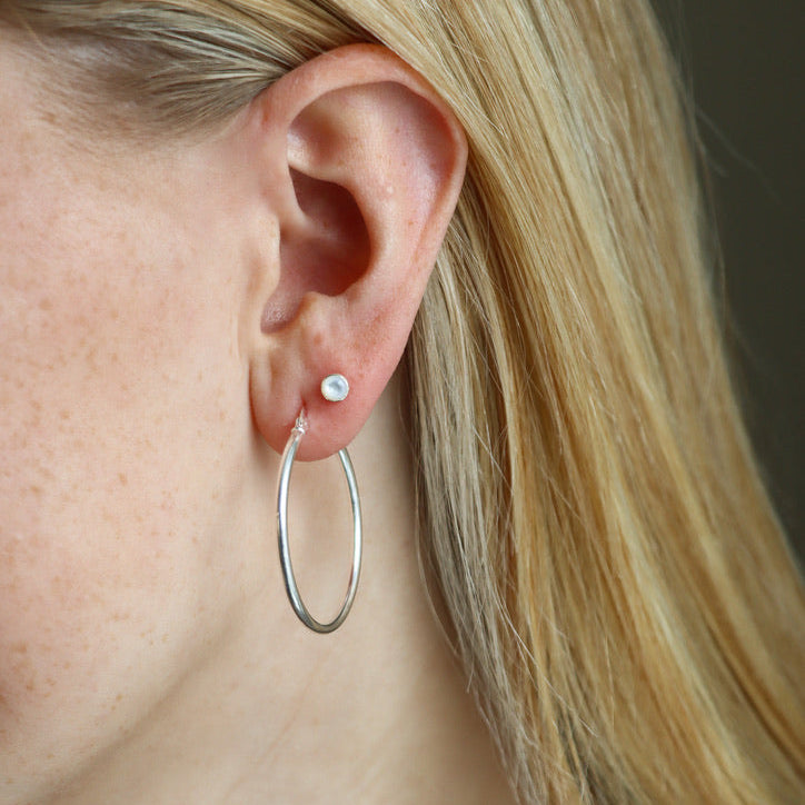 model wearing sterling silver studs with mother of pearl stones with large hoops