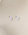 sterling silver round discs with marathon miles hand stamped on it on a light dish