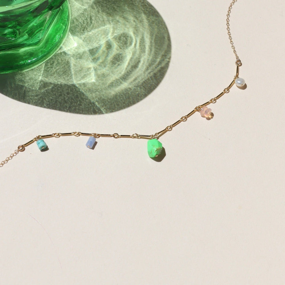 14k gold fill chain necklace with gemstone charms on a light surface