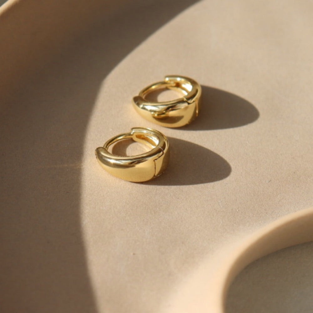 sleek gold huggie earrings sitting on a jewelry dish at Token Jewelry in Eau Claire, Wisconsin