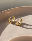 sleek gold huggie earrings sitting on a jewelry dish at Token Jewelry in Eau Claire, Wisconsin