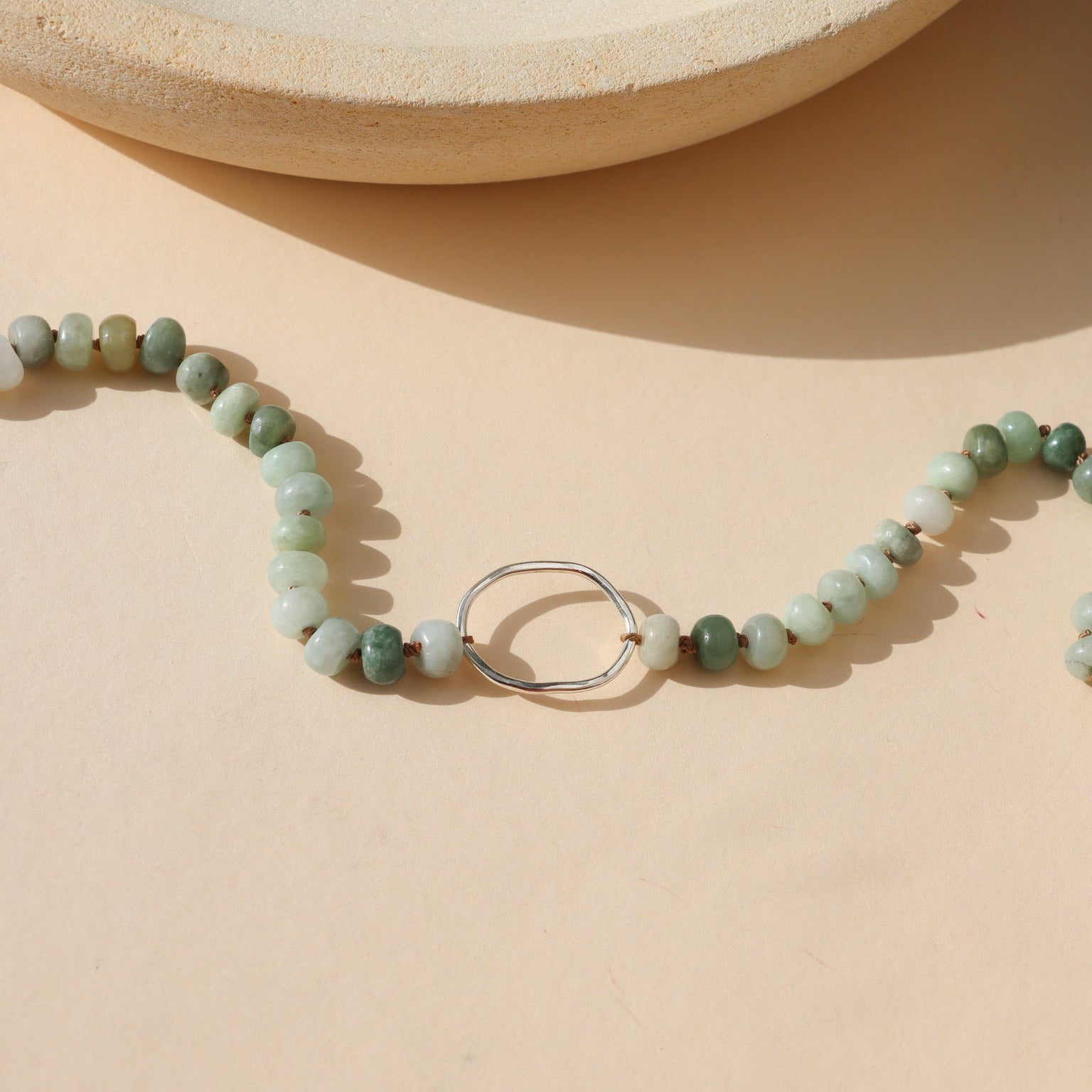 sterling silver handmade pendant with jade beads on a light background