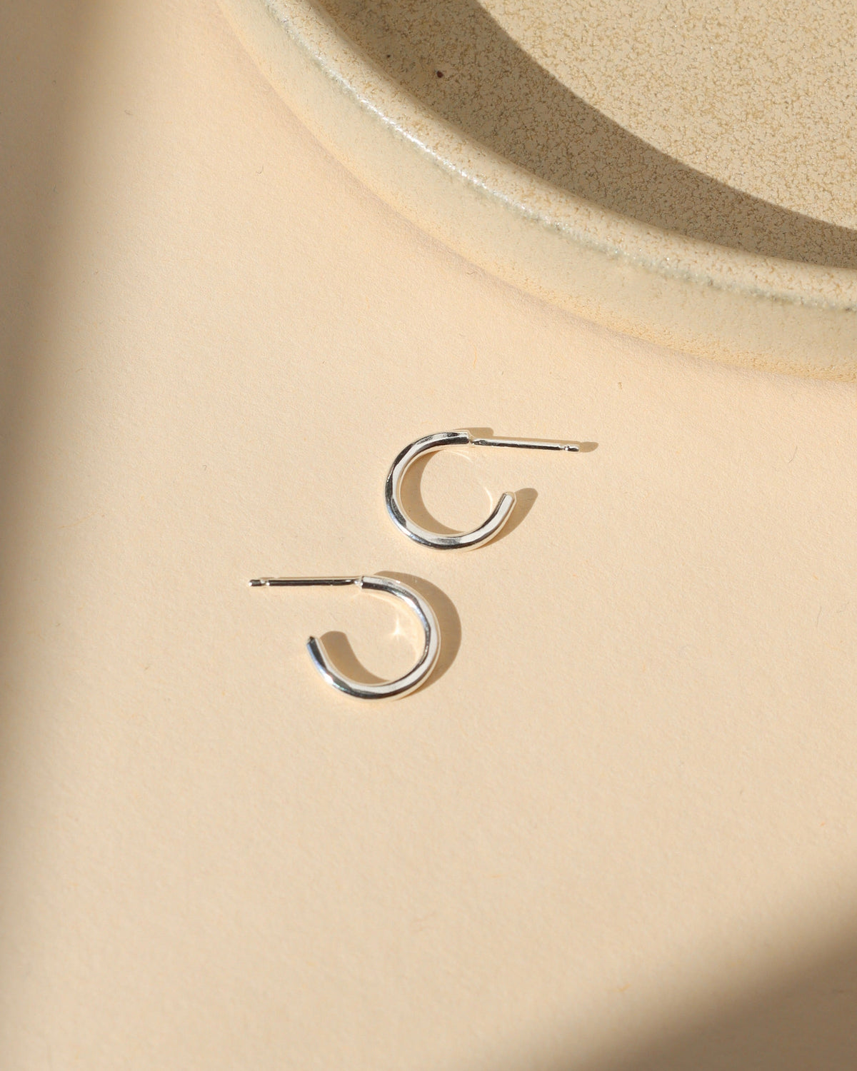 sterling silver hammered hoop earrings on a light dish