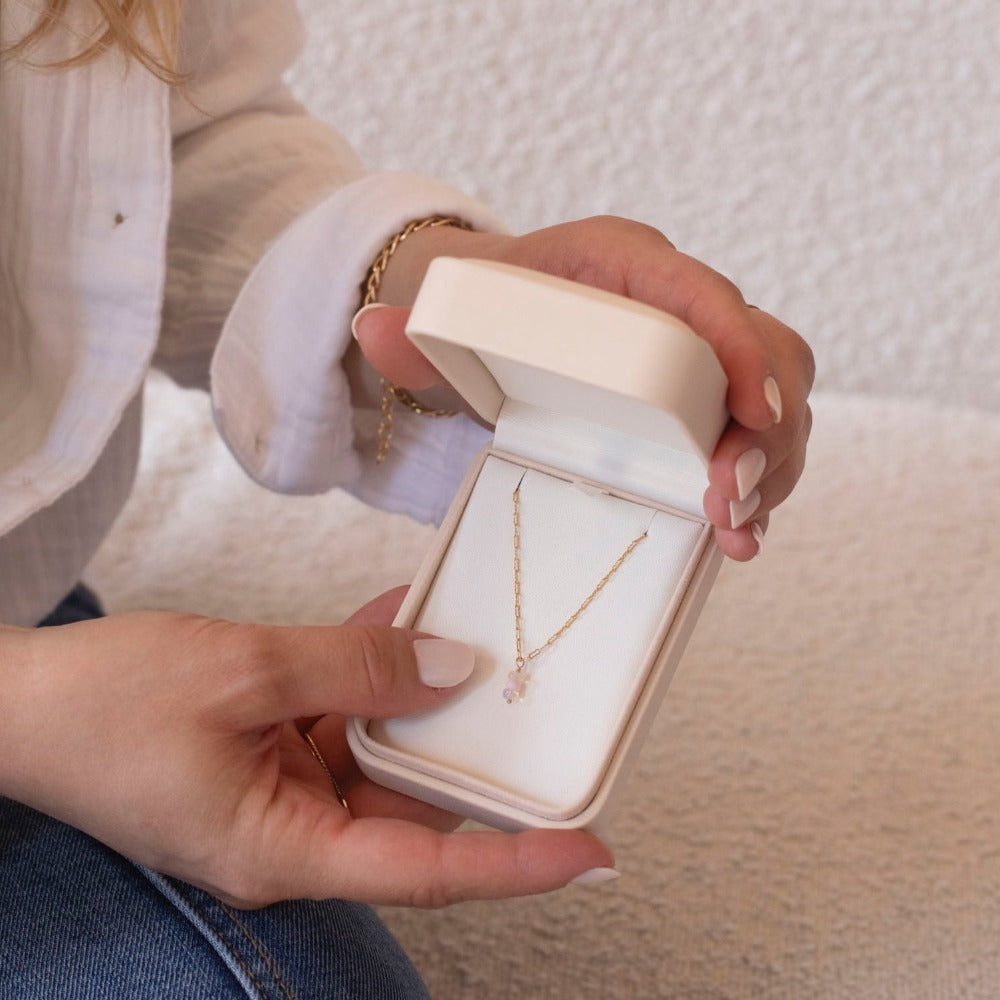 Model holding 14k gold fill Gender Reveal Necklace. This necklace features a beautiful mini paper clip chain that is met together with either a pink or blue opal gemstones.