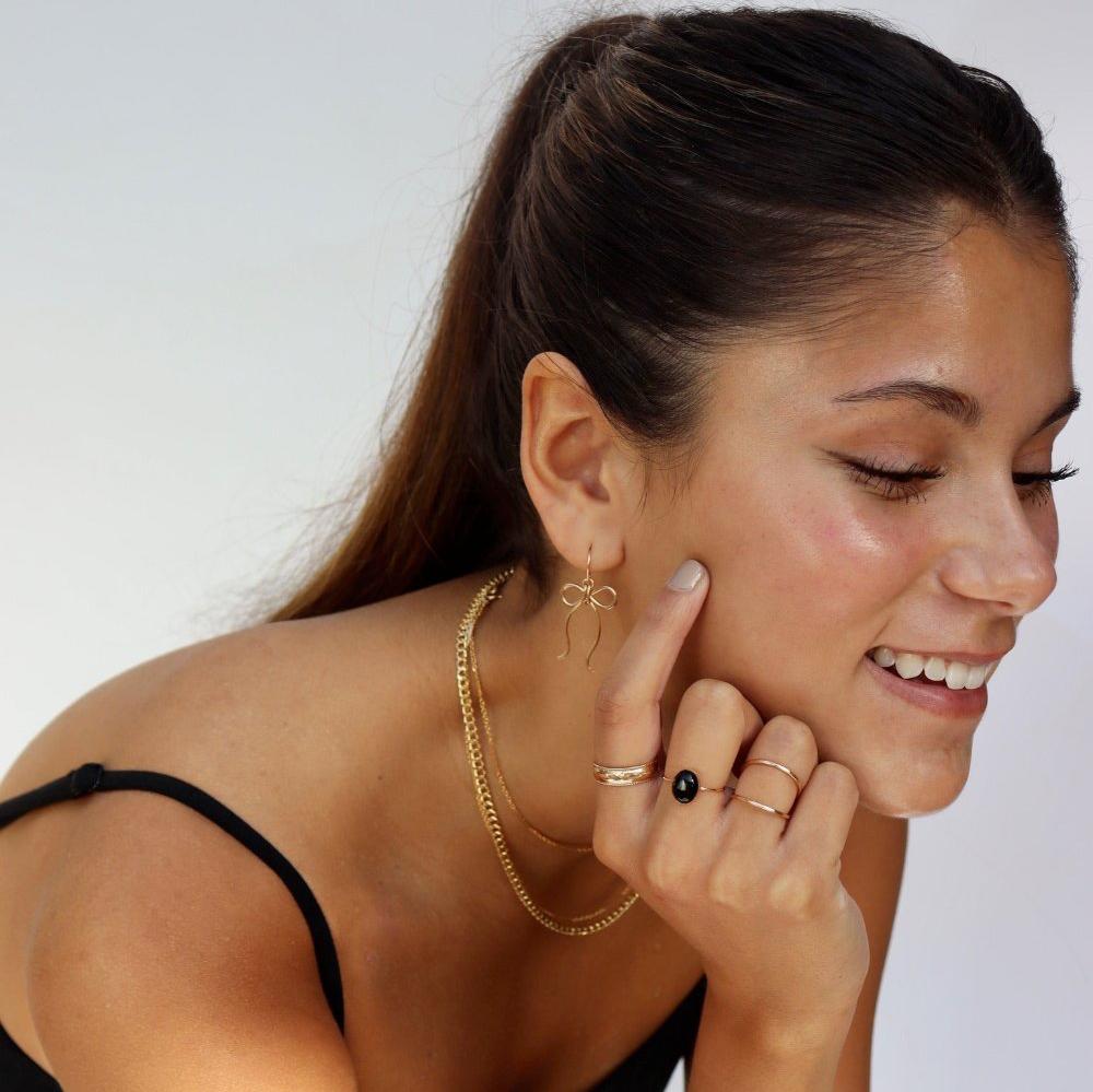 Brunette model wearing the laine ring. This ring features a gold hammered band with rippled edges. 