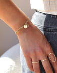 14k gold fill bold link chain Demi Alexandra Bracelet featuring two gold fill disks with a heart and an "S", worn by a model wearing black jeans and a white top