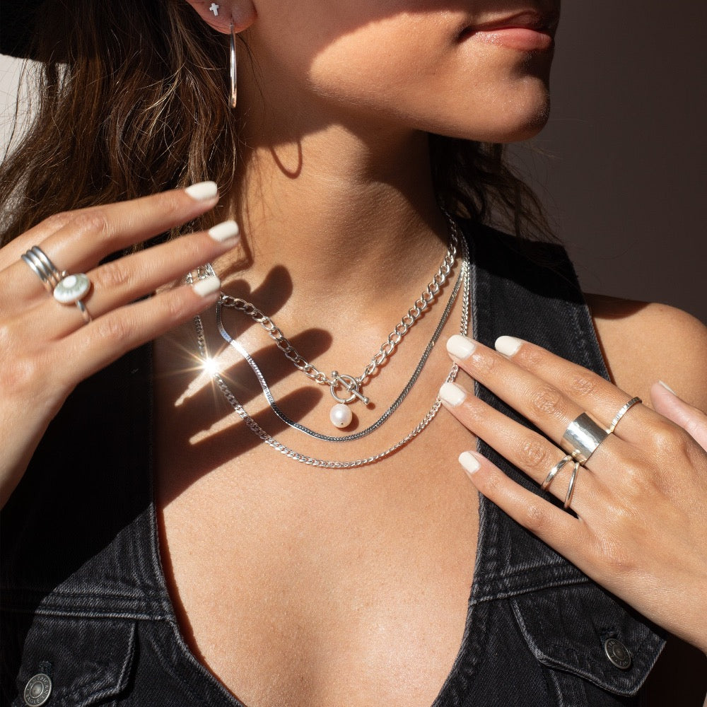 925 sterling silver chain with a toggle clasp and large pearl, photographed on a model wearing black and all silver jewelry