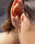 14k solid gold wire formed into arch shaped earrings with one hammered end, photographed on a brunette model