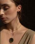 Brunette model wearing a 14k gold fill Lucky Charm Necklace. This Necklace features a horseshoe shape with hammering on one side. The horseshoe meaning lucky is connected with the simple chain.