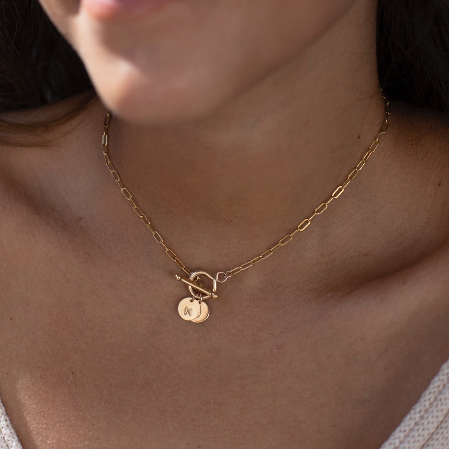 model found wearing 14k gold fill monogram toggle necklace. This necklace features the narrow link chain connected by a toggle with the monogram disc.