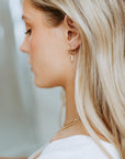 Model wearing 14k gold fill Petite Pearl Hoops, these earrings feature a petite hoops with three mini pearls hanging from the hoop. 