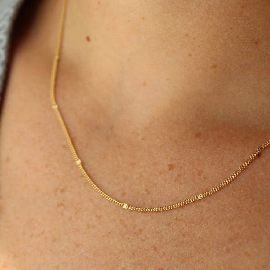 Model Wearing 14k Sunny chain. This necklace features a simple chain with an extra sparkle every 1/2&quot;.