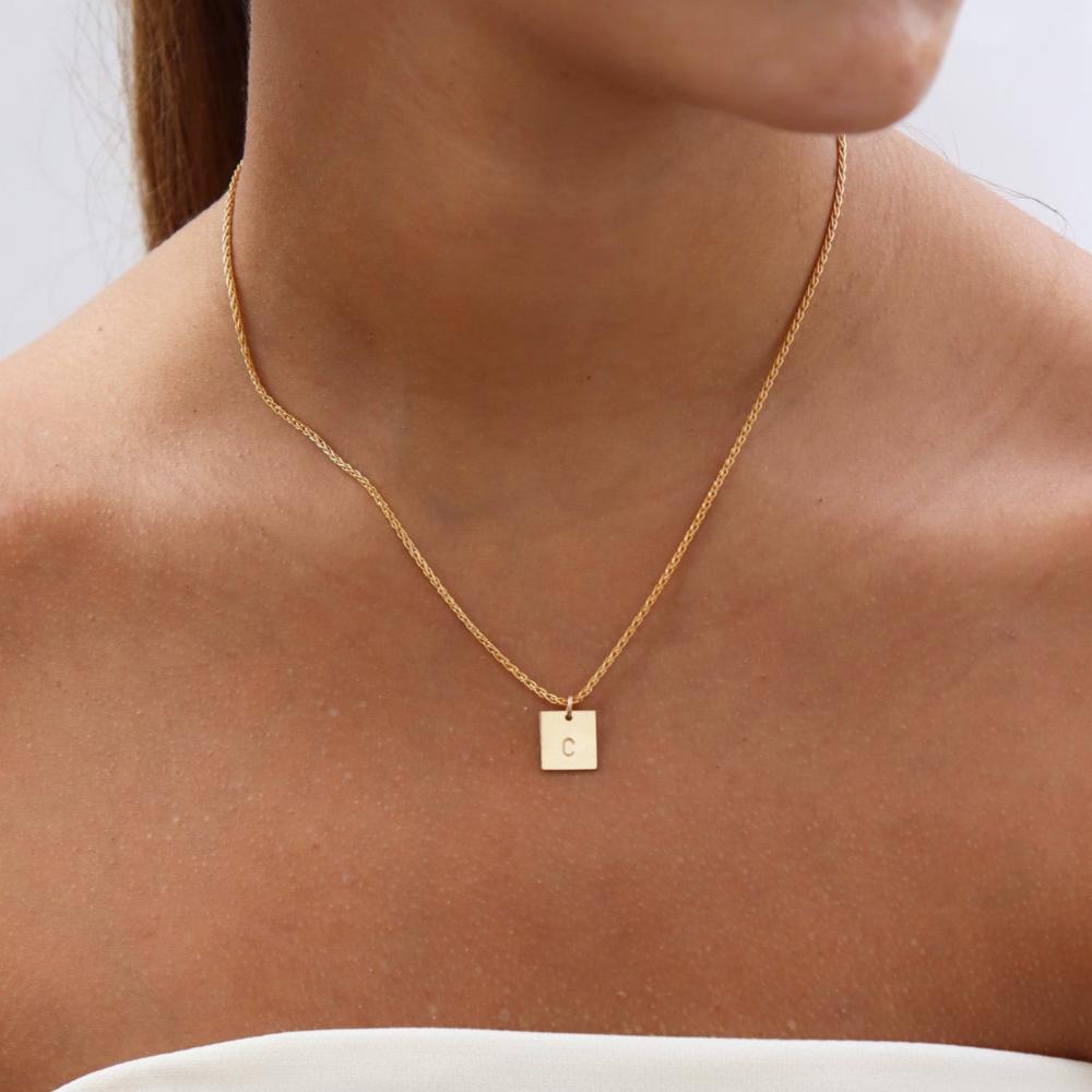 Brunette model wearing the westly monogram necklace. This necklace features a thin gold chain with a square stamped pendant with the letter "C."