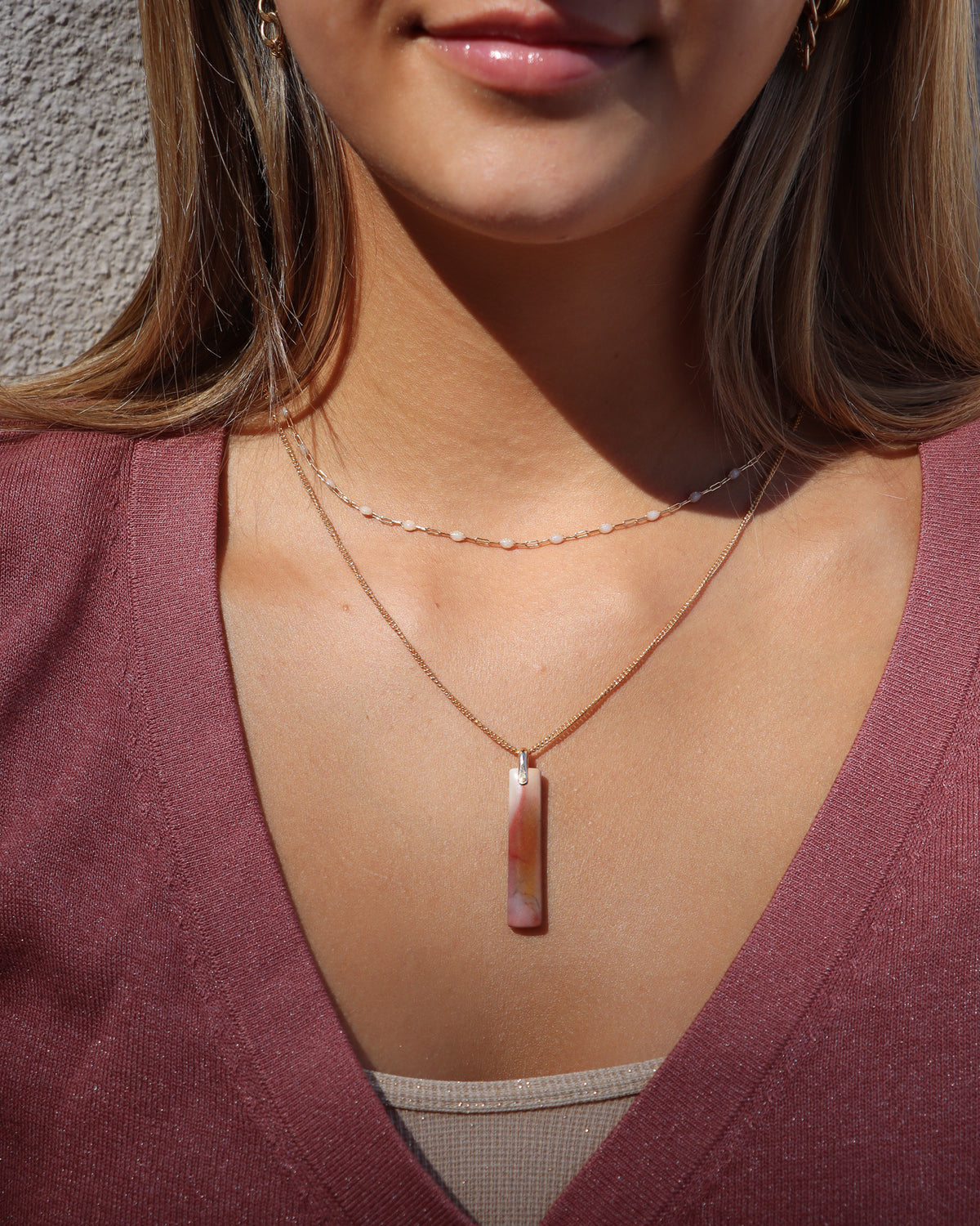 Rectangular pink, cream, and burgundy stone pendant necklace layered with a delicate gemstone chain.