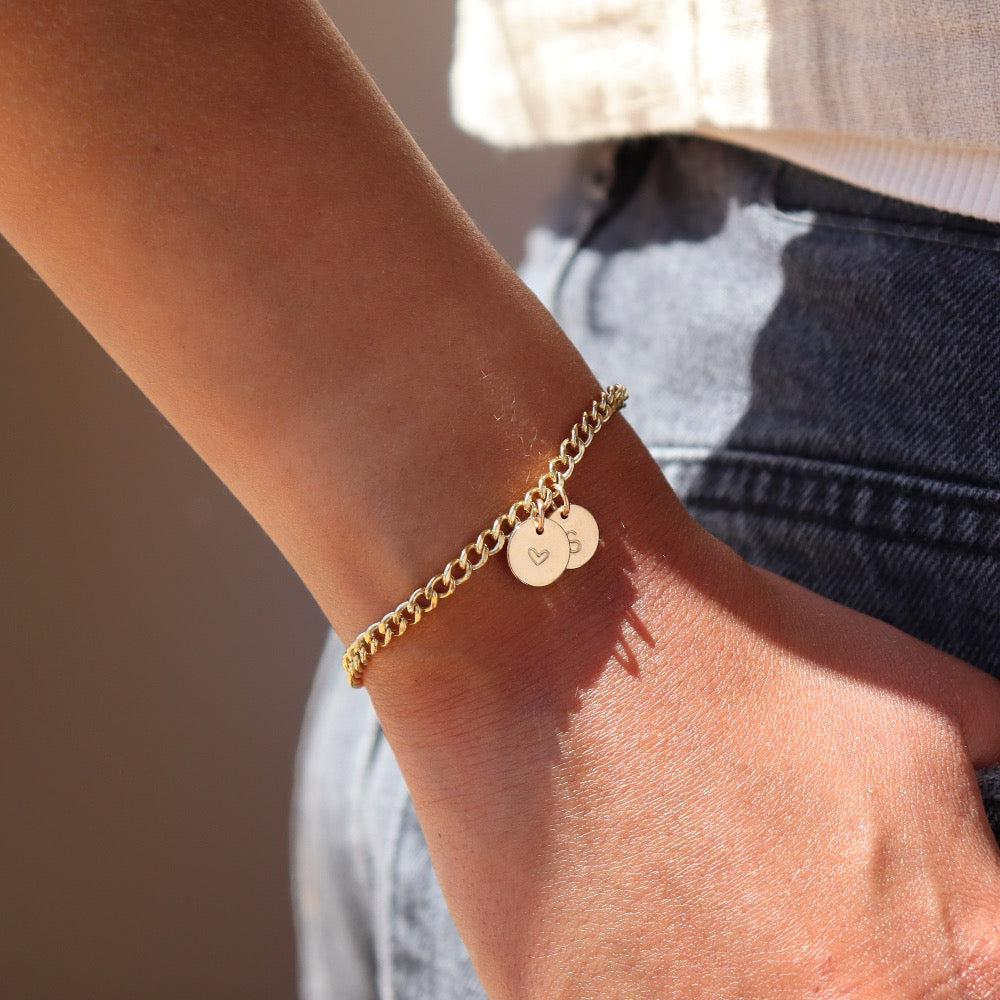 model wearing 14k gold fill curb chain bracelet with a heart and b hand stamped discs