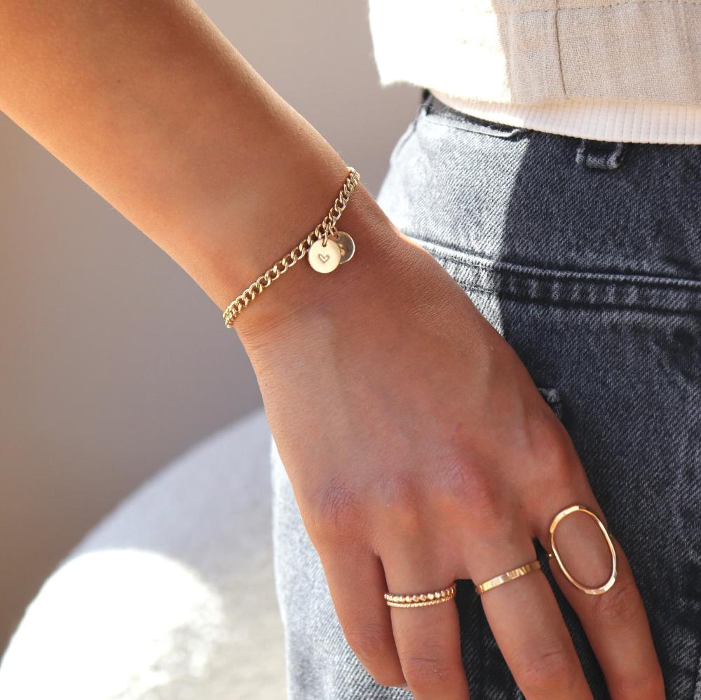 model wearing 14k gold fill curb chain bracelet with hand stamped discs paired with 14k gold fill band rings and an oval ring