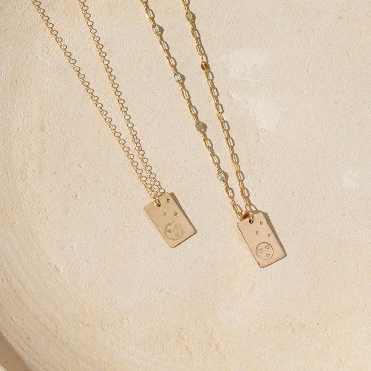 14k gold fill chain necklaces with hand stamped moon and star pendant on a light dish