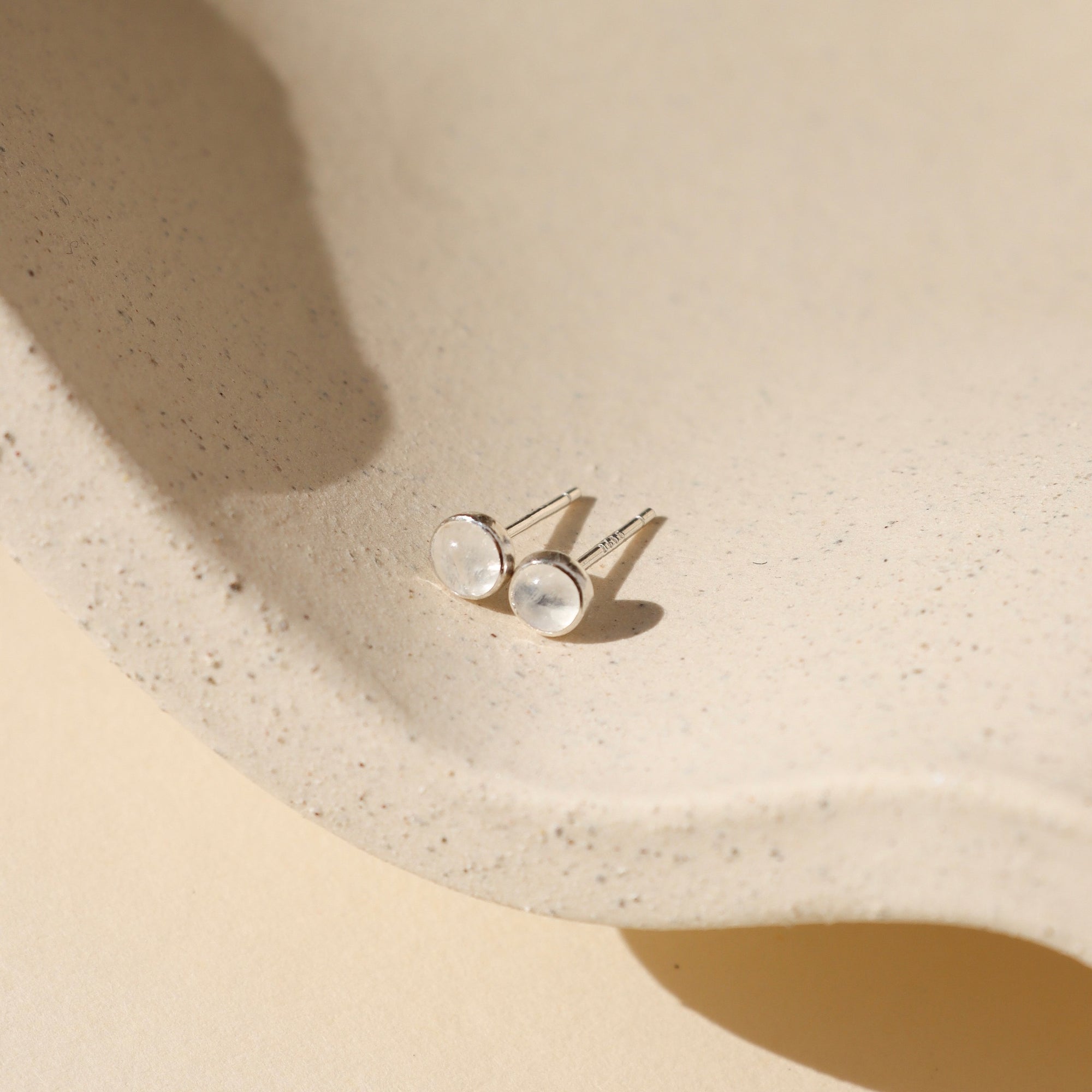 sterling silver bezel ear post with 4mm moonstones on a light dish
