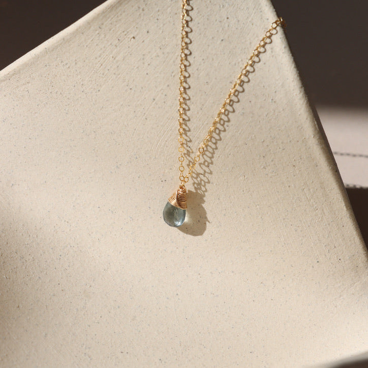 delicate 14k gold fill chain necklace with moss aquamarine stone on a light dish