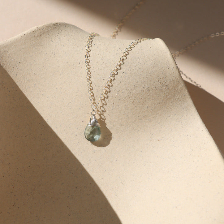 delicate sterling silver chain necklace with moss aquamarine stone on a light dish