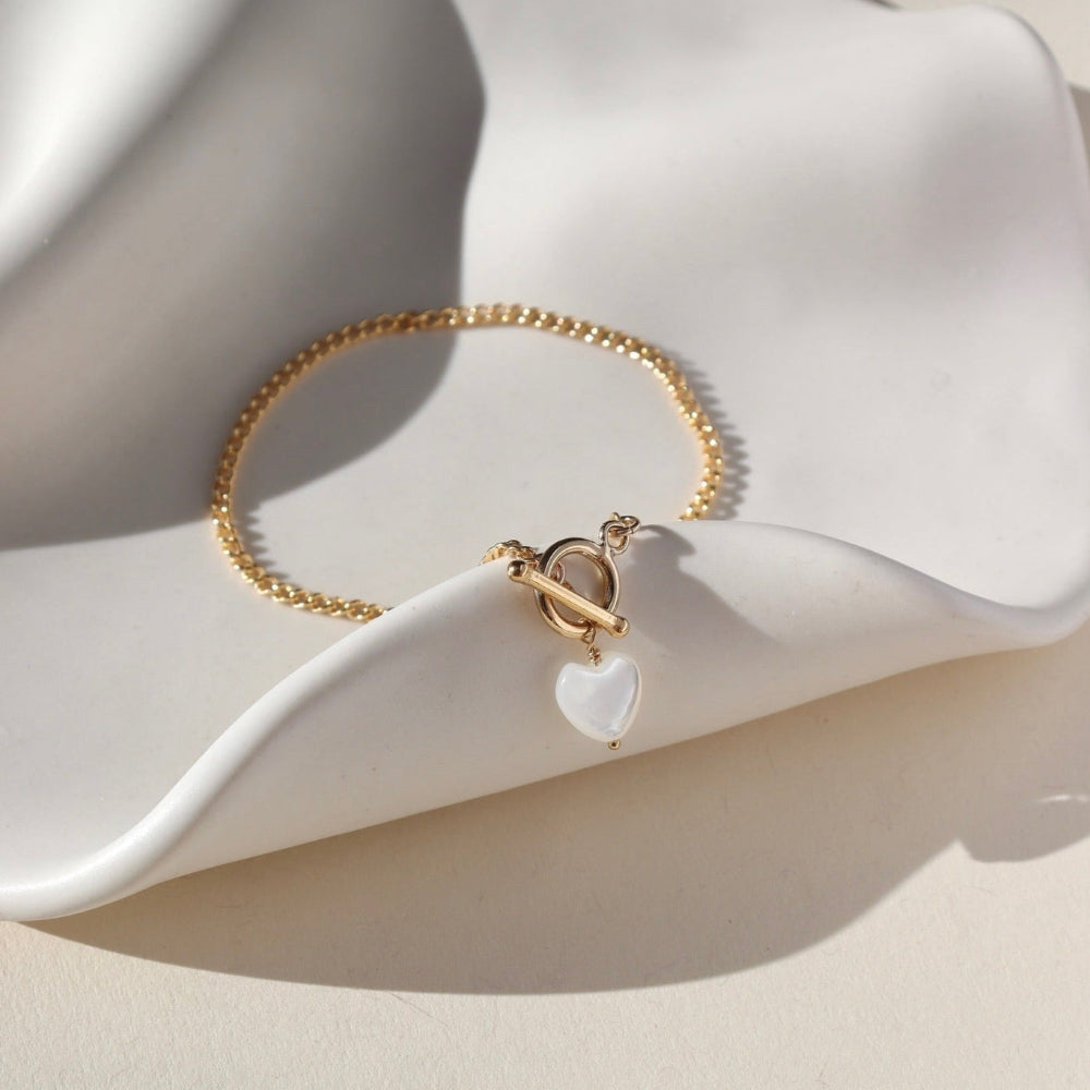 Bracelet by Token Jewelry - a 14k gold fill La Mer Chain with a toggle and a mother of pearl heart charm. This bracelet features a gold curb chain with a toggle clasp opening with a mother of pearl heart at the end. 