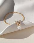 Bracelet by Token Jewelry - a 14k gold fill La Mer Chain with a toggle and a mother of pearl heart charm. This bracelet features a gold curb chain with a toggle clasp opening with a mother of pearl heart at the end. 