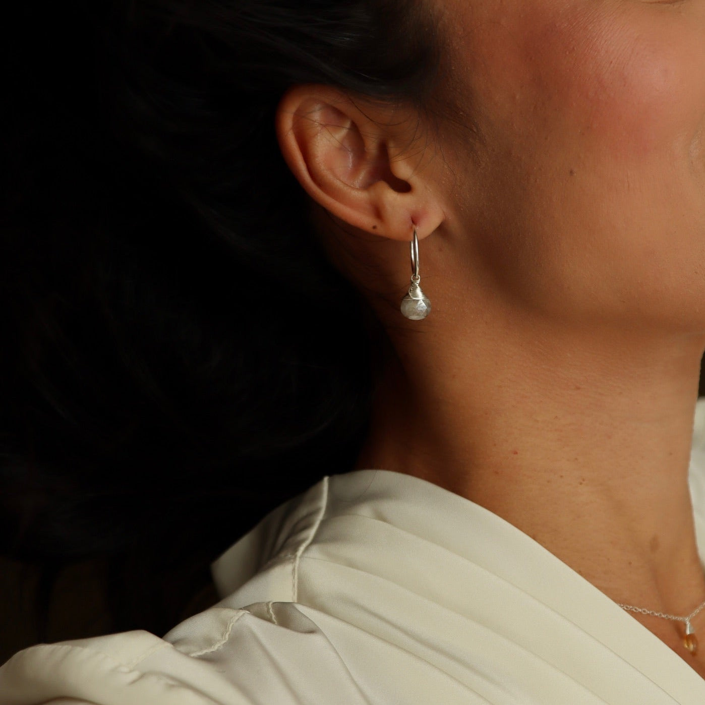 Gold hoop earrings featuring iridescent moonstone charms with soft, shimmering hues.