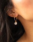 Gold hoop earrings featuring iridescent moonstone charms with soft, shimmering hues.