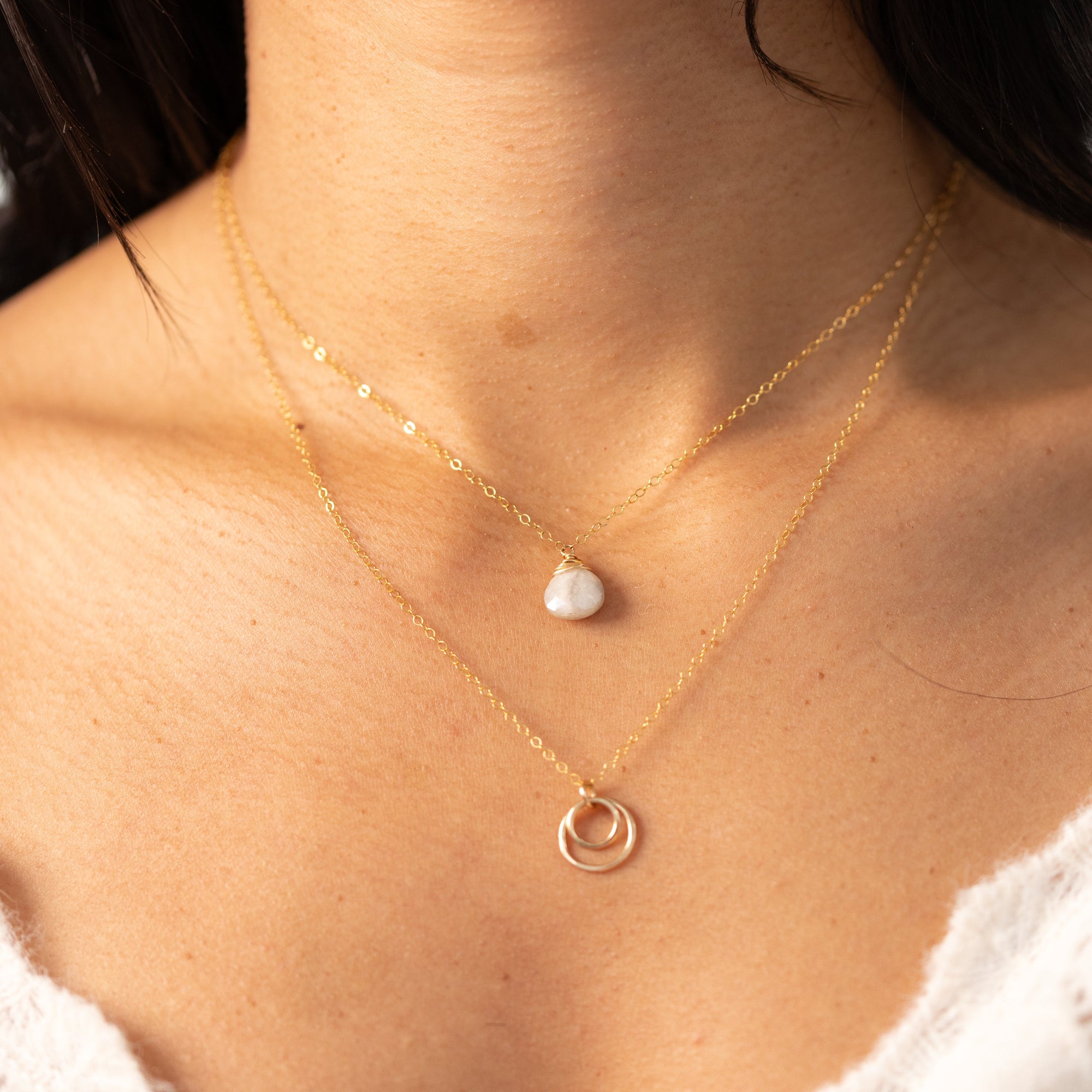 Delicate gold necklace featuring a shimmering oval moonstone pendant with iridescent hues.