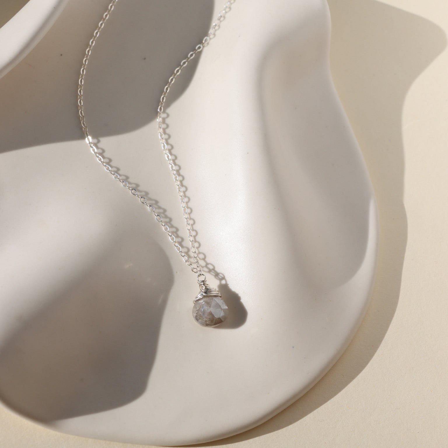 Delicate sterling silver necklace featuring a shimmering oval moonstone pendant with iridescent hues.
