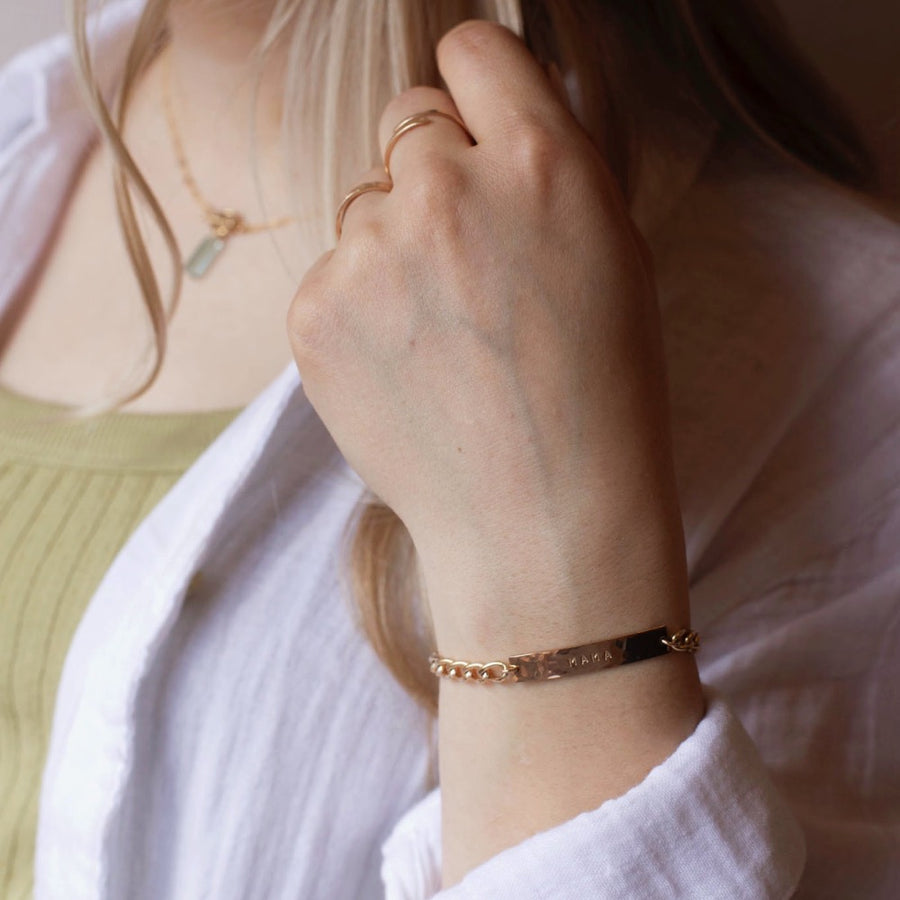 Model wearing 14k gold fill Alexandra Name Plate Bracelet. This Bracelet features a simple hammered Name plate that you get to customize with any character of your choice with 8 initials. The plate is connected by the Alexandra chain.