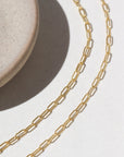 14k Gold fill Narrow Links chain laid on a white paper in the sunlight.