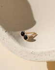 Gold ring with black stones on a beige surface