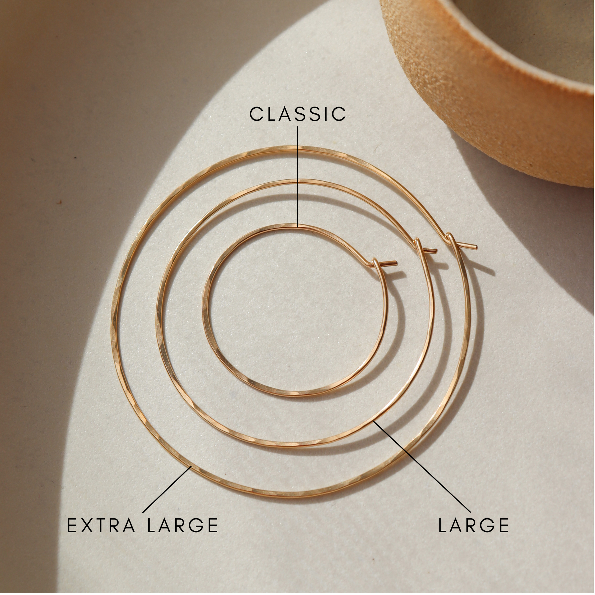 14k gold fill hoop earrings on display showing the different sizes on a light table