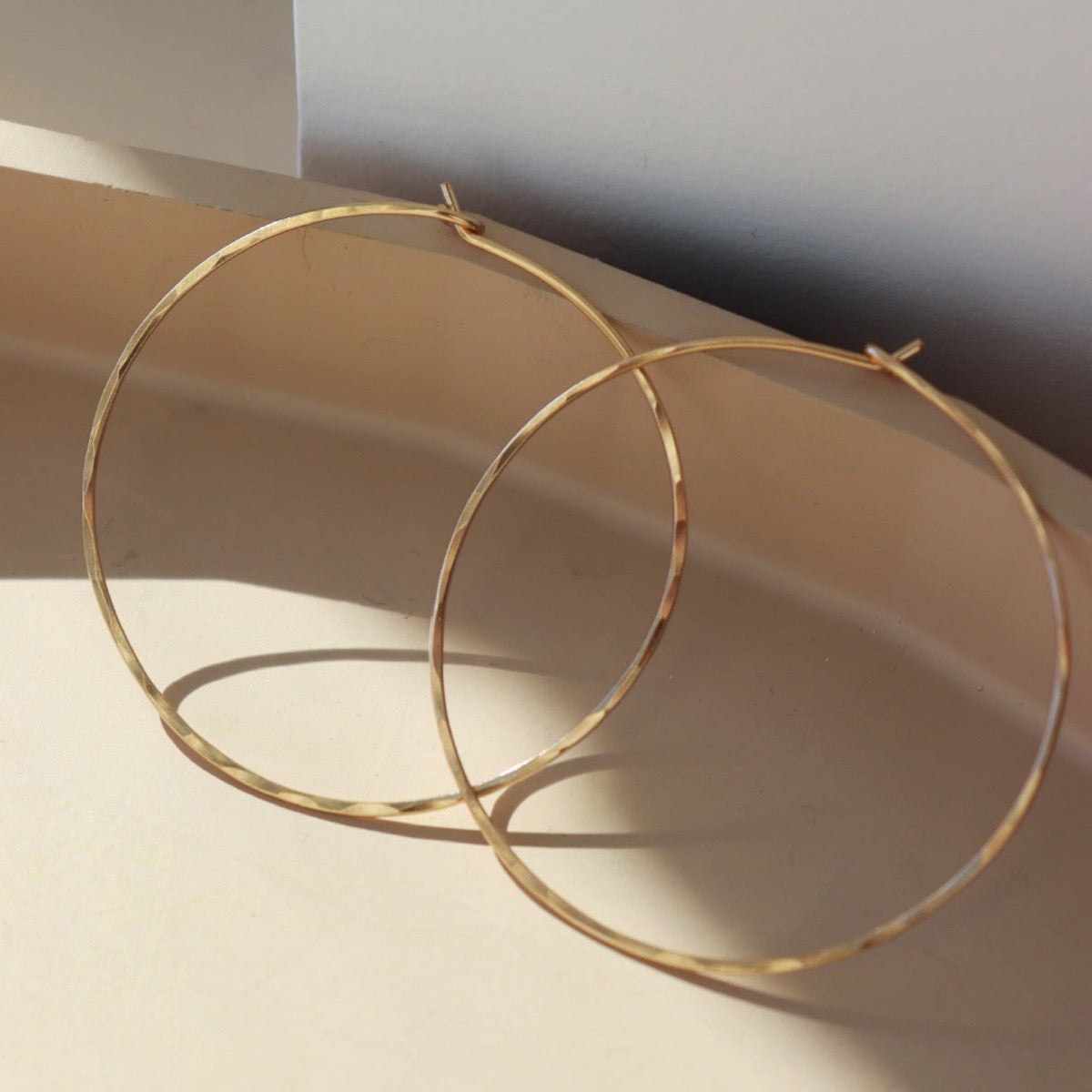 14k gold fill hammered hoop earrings on a light dish